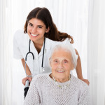Portrait Of Happy Female Doctor With Handicapped Senior Patient In Hospital